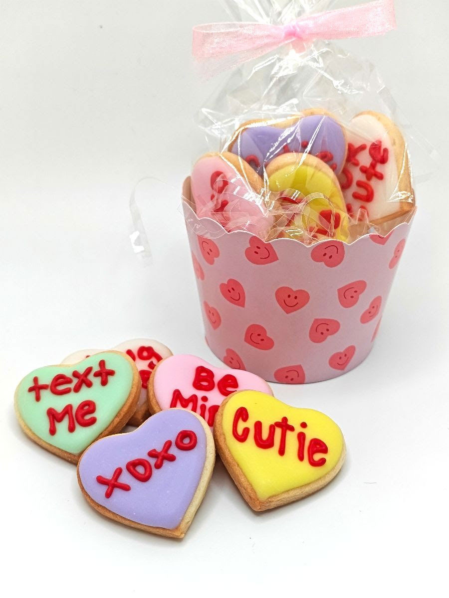 Different colored Valentines cookies in a cup.